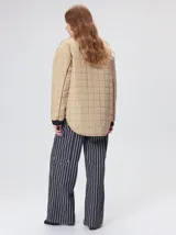 Campera reversible capitoneada con cierre frontal. Un lado es de color negro y el otro es de color beige, ambos con diseño acolchado. Cuenta con cuello redondo, mangas largas y bolsillos laterales.