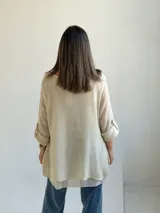 Sweater de punto color beige, de corte amplio y holgado, con escote redondo y mangas largas con presillas para arremangar.