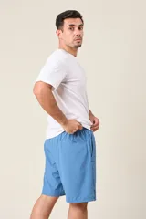 Bermuda deportiva de nylon color gris, de corte suelto, con cintura elástica y cordón de ajuste. Cuenta con detalles de líneas negras en los costados y bolsillos laterales con cierre.