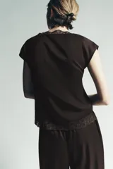 Top color marrón oscuro, con escote en V y mangas cortas. Presenta detalles de pliegues verticales en el delantero y terminaciones con encaje a tono en el escote y el ruedo inferior.