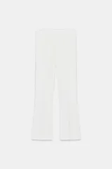 Pantalón mini flare de tiro medio y color blanco, con bajo acabado en línea evasé y cierre lateral con cremallera oculta en costura.