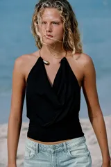 Top de poliamida color negro con escote drapeado y cuello halter que incorpora un detalle de choker metálico dorado.