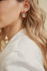 Aros tipo caravana con diseño floral, compuestos por una piedra central transparente facetada rodeada de pétalos de resina en color terracota.