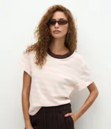 Blusa de corte boxy con mangas cortas, confeccionada en algodón. Presenta un diseño de rayas horizontales en tonos crema y rosado, con un cuello redondo de punto en color marrón oscuro que genera contraste.