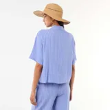 Camisa azul de manga corta con diseño de rayas verticales blancas, cuello camisero y cierre frontal con botones.