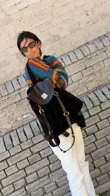Mochila Brassy confeccionada en combinación de gamuza marrón oscuro y cuero negro, con solapa de cuero texturado y herrajes metálicos en tono oro viejo. Presenta correas regulables y diseño funcional para el día a día.