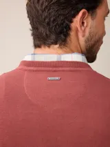 Sweater de punto con cuello en V, manga larga y puños acanalados. Presenta un pequeño logo bordado en el pecho.