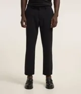 Pantalón de vestir para hombre, color beige claro, de corte slim y sastrería. Presenta cierre frontal con botón y cremallera, y bolsillos laterales y traseros.