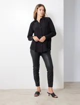 Camisa de satén color violeta, con cuello clásico, cierre frontal con botones, manga larga con puños anchos abotonados y bolsillo aplicado en el pecho.
