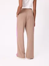 Babucha de corte holgado en color beige con paneles laterales en color fucsia y vivos blancos. Presenta cintura elástica y logo bordado en la parte superior.