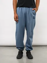 Pantalón de jogging de felpa con friza, color gris, con cintura elástica, bolsillos laterales y puños en los tobillos. Presenta un parche con el logo de Umbro en la parte superior delantera.