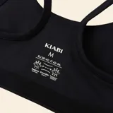 Sujetador deportivo negro con diseño de espalda nadadora, confeccionado en tejido elástico y transpirable, ideal para actividades de impacto medio.