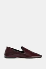 Zapato plano tipo slipper confeccionado en piel color bordó, con diseño de copete subido, punta cuadrada y talón flexible que permite su uso como destalonado.