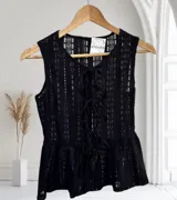 Blusa sin mangas de encaje con detalle de lazo en el escote y corte peplum.