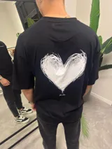 Remera negra de algodón con estampado de un corazón blanco en la espalda.