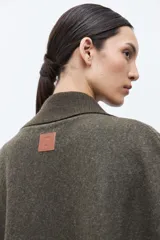 Capa de tejido de punto en color verde oliva, con diseño abierto, solapas tipo blazer y cuello clásico. Presenta una caída fluida y corte holgado.