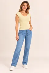 Remera de punto color manteca, de corte ajustado sin mangas, con escote redondo y detalles de apliques de perlas pequeñas en el cuello y las sisas.