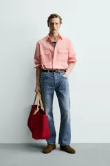 Camisa de corte relajado color celeste, confeccionada en mezcla de algodón y seda. Presenta cuello solapa, cierre frontal de botones, manga larga con puños abotonados y dos bolsillos de plastrón con solapa en el pecho.
