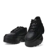 Championes Puma modelo Karmen, de diseño urbano con plataforma elevada. Presentan un exterior sintético en color negro, con cordones al tono y detalles metálicos en los ojales superiores. Su suela robusta de goma proporciona estabilidad y un estilo moderno.
