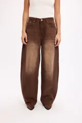 Pantalón de jean estilo baggy, color marrón con efecto desgastado y textura de pana. Presenta un corte holgado, tiro alto y diseño de cinco bolsillos con cierre de botón y cremallera.