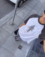 Remera estilo raglán con cuerpo blanco y mangas cortas negras. Presenta un estampado frontal con un galgo en movimiento y la palabra KABOA en color fucsia.