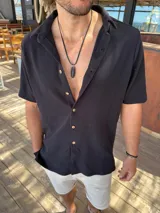 Camisa de manga corta con textura tipo waffle, color negro, con cuello clásico y cierre frontal de botones claros.