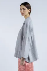 Sweater gris de punto con cuello redondo, mangas amplias y terminaciones acanaladas.