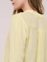 Blusa de gasa bambúla color amarillo, marca Zac & Rachel, con cuello a la base y escote en V con botones frontales. Presenta diseño delantero plisado y mangas largas con sistema de ajuste mediante presilla.