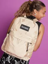 Mochila clásica de color beige con acabado satinado, marca Terrano. Cuenta con un compartimento principal con cierre, un bolsillo frontal amplio con cierre y bolsillos laterales. El interior incluye una división para notebook. Presenta un parche frontal negro con el logo de la marca.