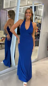 Vestido largo de fiesta color azul eléctrico con acabado brillante. Presenta un diseño con escote halter profundo, espalda descubierta y detalle de fruncido en la cintura que estiliza la figura.
