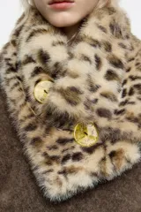 Cuello de pelo sintético con estampado animal print en tonos beige y blanco, con cierre de botones frontales.