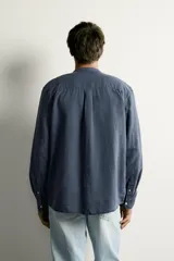 Camisa de corte relajado, confeccionada en mezcla de lino y algodón. Presenta cuello tipo mao, manga larga con puño abotonado y cierre frontal con botones.