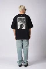 Remera negra de corte oversize con cuello redondo y mangas cortas. Presenta un pequeño estampado gráfico en color blanco en el centro del pecho.