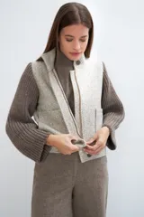 Campera de lana fina color crema, con cuerpo estructurado y mangas de tejido de punto acanalado. Presenta cuello alto, cierre frontal con botones y bolsillos laterales con doble abertura.