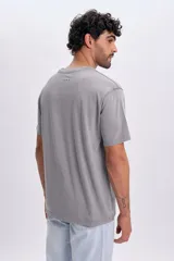 Remera gris claro de manga corta, con cuello redondo y estampa sutil con la inscripción "Athletics" en el pecho.