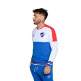 Buzo de fútbol Umbro del Club Nacional de Football, con diseño de bloques de color blanco, azul y rojo. Incluye logo de Umbro y escudo del club.