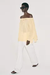 Blusa de lino color blanco, con escote recto ajustable mediante cordón y hombros descubiertos. Cuenta con manga larga abullonada terminada en elástico.