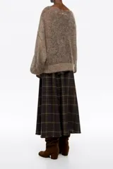 Falda midi de corte línea A, confeccionada en mezcla de lana con estampado de cuadros en tonos verde oscuro, rojo y beige. Presenta cierre lateral oculto, costuras diagonales abiertas y acabados sin rematar en el dobladillo.