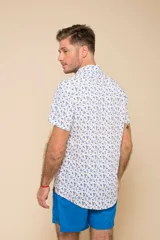 Camisa celeste con estampado floral blanco, de manga corta y corte clásico. Cierre frontal con botones.