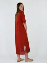 Vestido midi de punto color beige, con cuello solapa, mangas cortas y cierre frontal con botones. Presenta detalles de costuras y terminaciones en color mostaza, además de un diseño calado en el sector inferior de la falda.