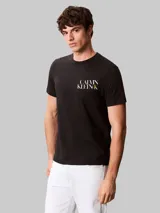 Remera de algodón negro con cuello redondo y mangas cortas. Presenta un diseño gráfico con el logo de la marca estampado en el pecho en color blanco y amarillo.
