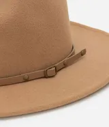 Sombrero estilo cowboy color camel con textura de gamuza y detalle de correa fina con hebilla metálica alrededor de la base.
