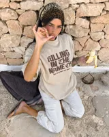 Remera oversize color beige con efecto acid wash y estampa frontal en marrón con la frase "Killing In The Name Of".