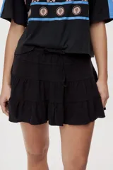 Falda corta blanca con diseño de volados escalonados y cintura elastizada, de silueta fluida y liviana.