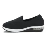 Zapato casual tipo slip-on de lycra color negro, con suela de plataforma blanca y cámara de aire en el talón. Presenta un aplique circular metálico con logo en el empeine.
