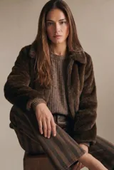 Abrigo de piel sintética en color marrón, con cuello clásico, cierre frontal con cremallera y mangas largas.