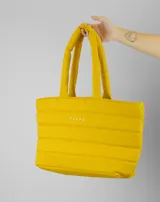 Bolso tipo shopper de diseño acolchado con costuras horizontales, color amarillo. Cuenta con doble asa de hombro y logo de la marca estampado en el frente.