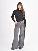 Jean de corte wide leg en color gris, con diseño de paneles laterales en tono más oscuro y ruedo desflecado.