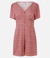 Enterito corto color rosa con estampado floral, escote en pico, botones y mangas cortas holgadas.