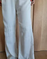 Pantalón de algodón color arena, de corte recto y holgado, con cintura elástica y detalle de costuras horizontales decorativas en la parte inferior de las piernas.